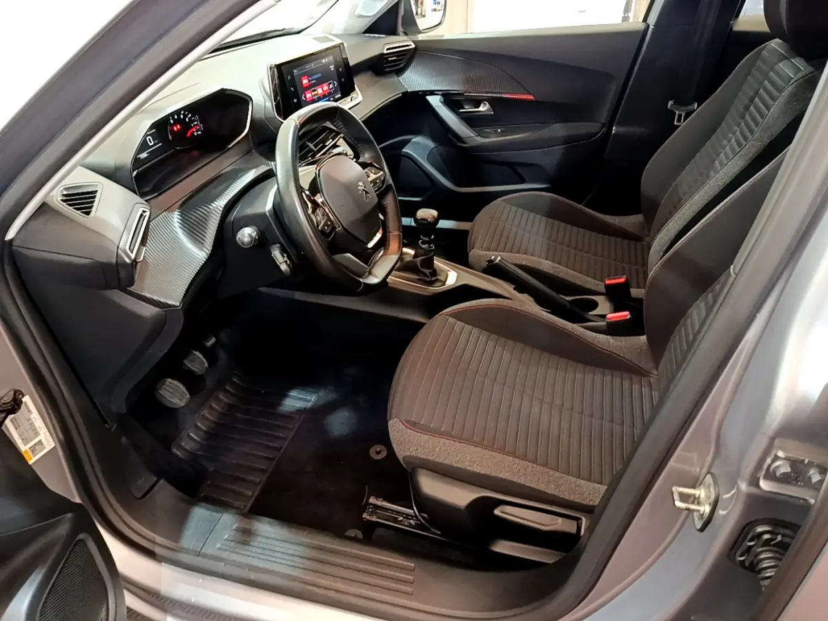 Intérieur avant droit d'une Peugeot 2008 gris clair 2020, volant cuir, écran tactile et sièges tissu gris.