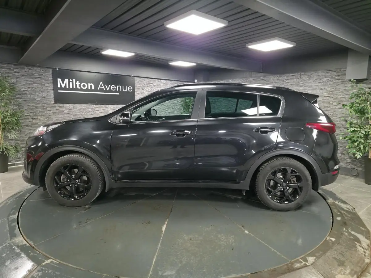 Vue de profil côté gauche d'un KIA Sportage noir Black Edition 2021 avec jantes alliage noires et toit panoramique.