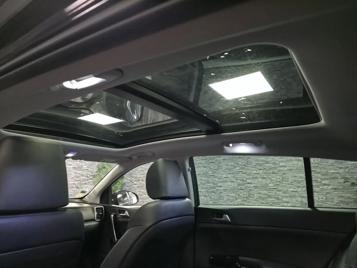 Intérieur noir du Kia Sportage 2021 vu côté droit, avec toit vitré panoramique et sièges cuir.
