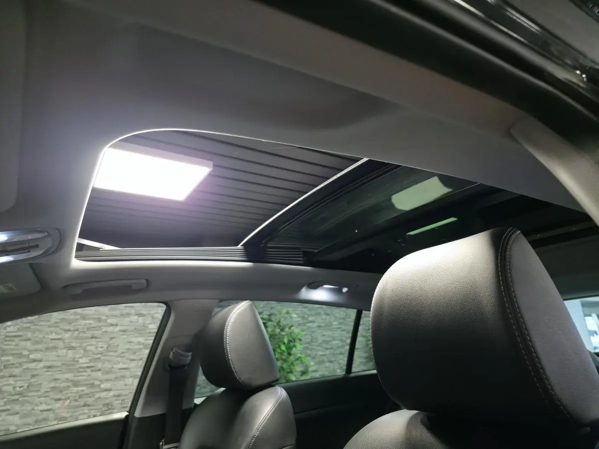 Vue intérieure du toit vitré panoramique ouvert du Kia Sportage noir avec sièges avant en cuir noir.
