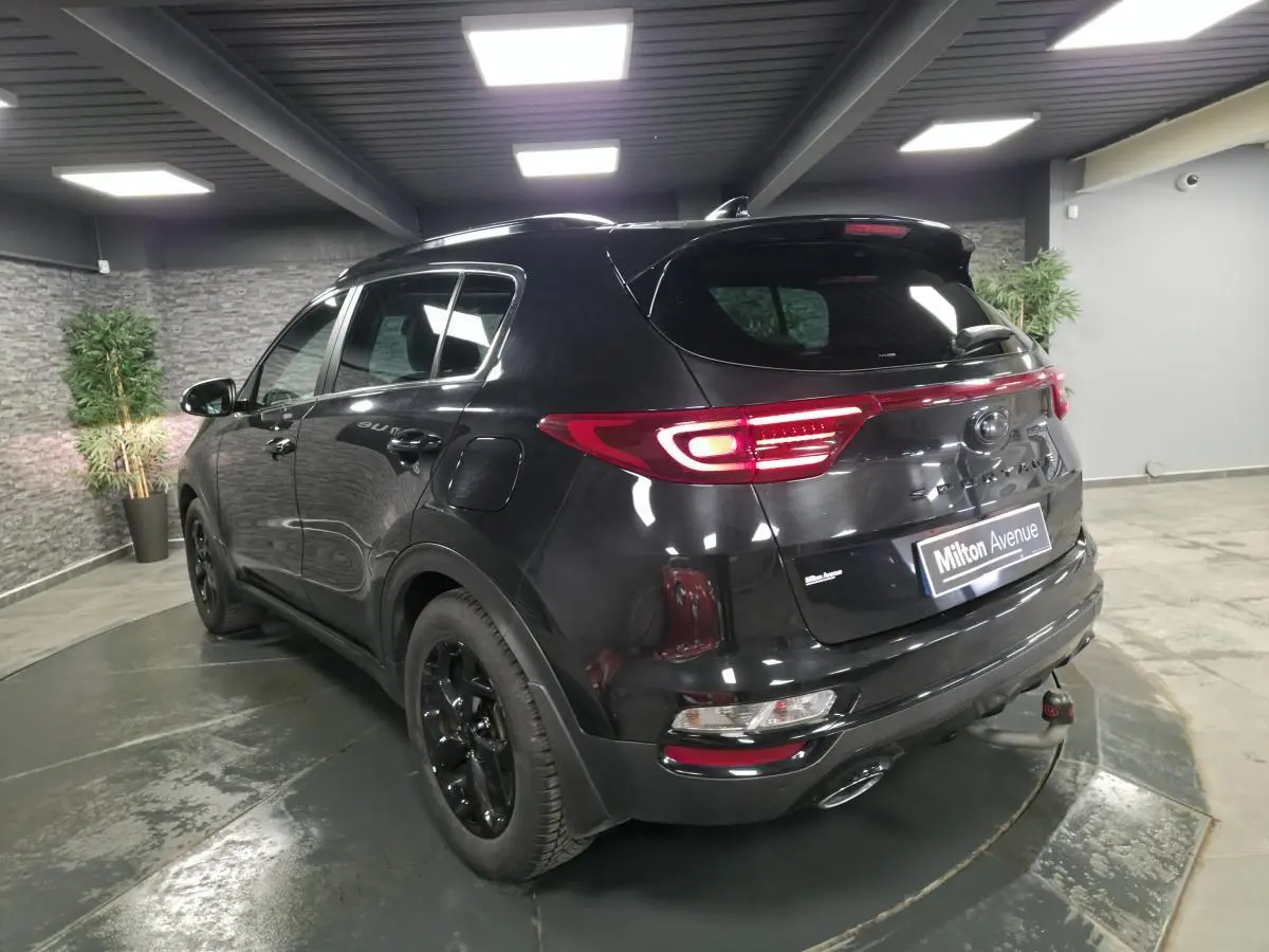 Vue 3/4 arrière gauche d'un KIA Sportage noir Black Edition avec feux arrière LED et jantes alliage noires.
