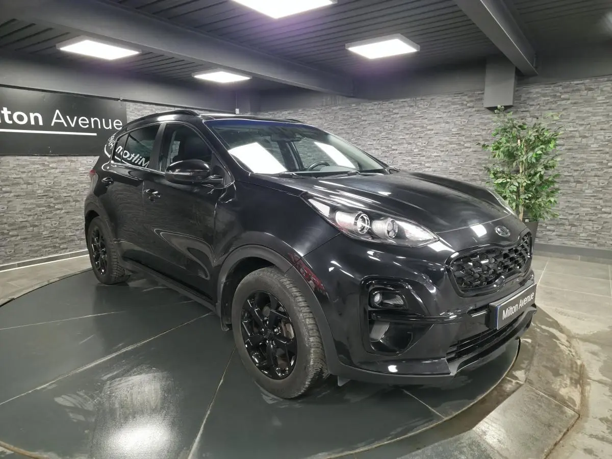 KIA Sportage noir 3/4 avant droit en intérieur avec jantes noires et calandre Black Edition.