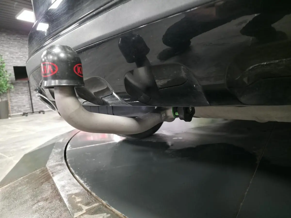 Gros plan sur l'attelage de remorque gris sous le pare-chocs arrière noir métallisé du KIA Sportage Black Edition.