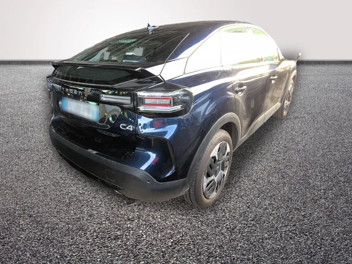 Vue 3/4 arrière droite d'une Citroën C4 hybride bleu foncé avec feux arrière LED et spoiler de coffre.