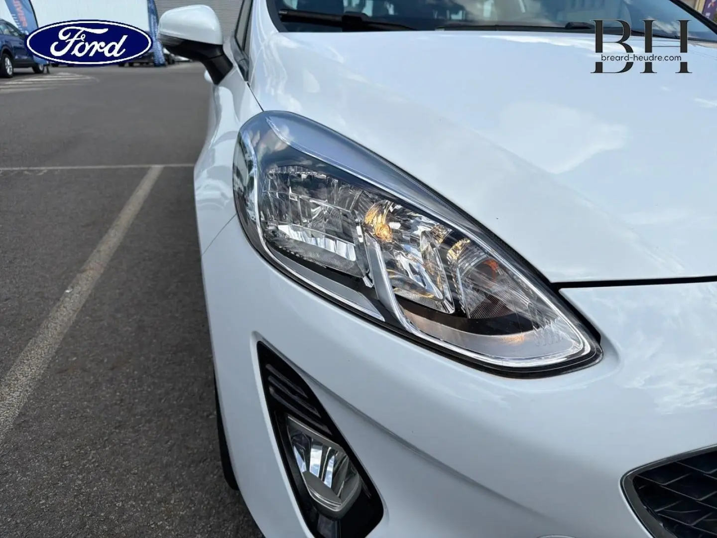Gros plan sur l'avant droit blanc glacier d'une Ford Fiesta 2020, mettant en valeur le phare et le feu antibrouillard.