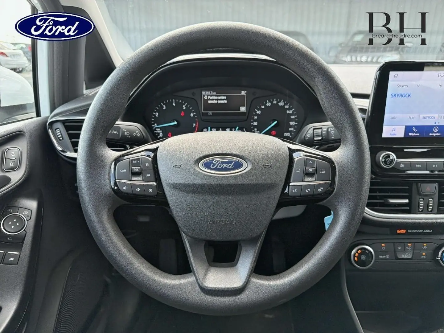 Vue intérieure centrée sur le volant noir de la Ford Fiesta 2020 avec tableau de bord et écran tactile visibles.