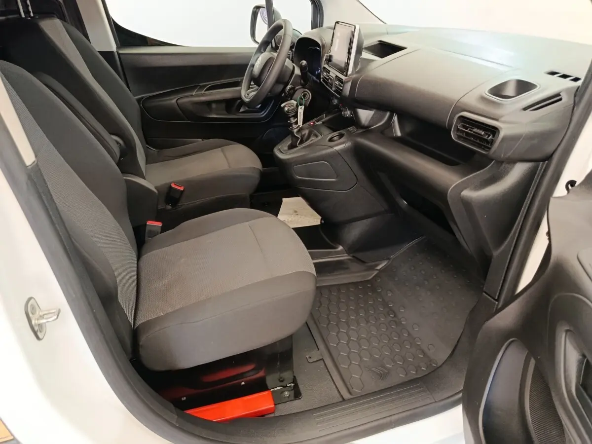 Vue intérieure côté conducteur du Citroën Berlingo blanc 2022, montrant sièges avant et tableau de bord noir.