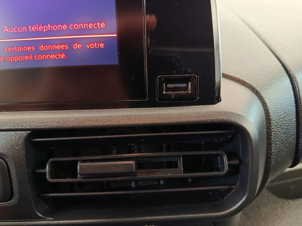 Détail intérieur du tableau de bord du Citroën Berlingo blanc 2022, avec prise USB et écran tactile.