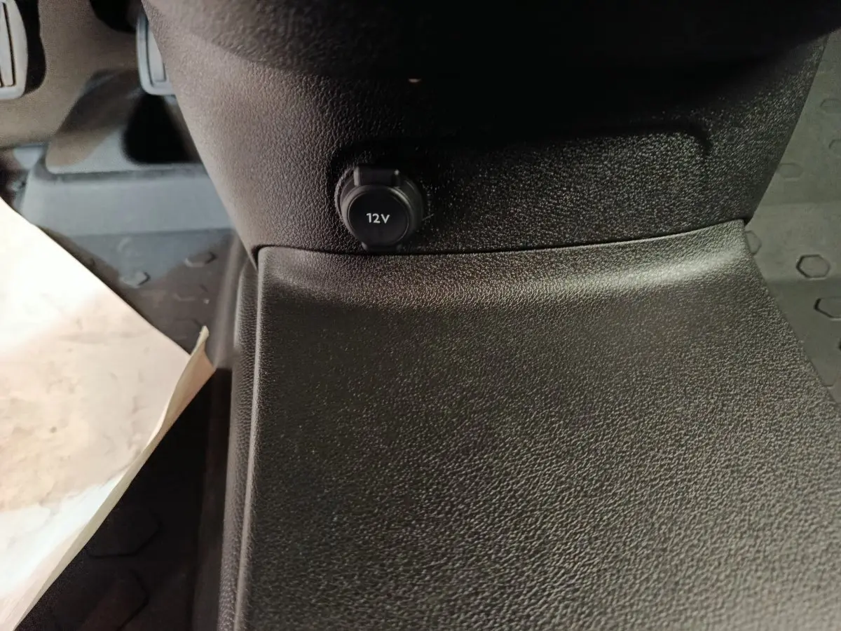 Prise 12V en gros plan sur la console centrale intérieure du Citroën Berlingo blanc, version 2022.