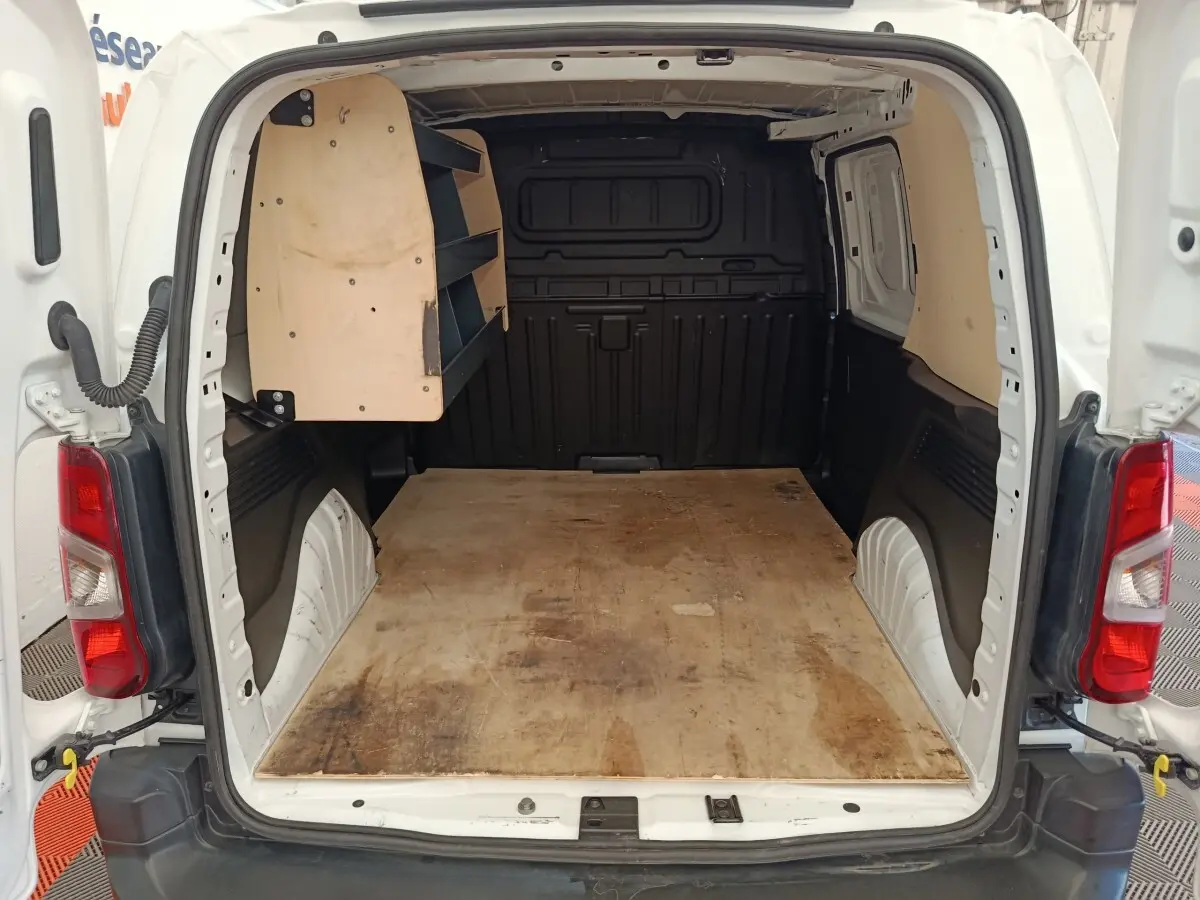 Vue arrière ouverte du Citroën Berlingo blanc montrant l’espace de chargement avec étagères en bois côté gauche.