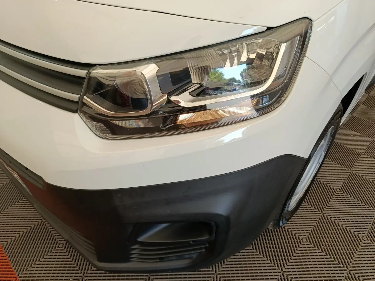 Gros plan sur le phare avant droit blanc du Citroën Berlingo 2022 avec pare-chocs noir et calandre grise.