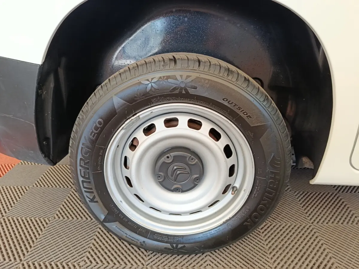 Gros plan sur la roue avant droite en jante acier grise du Citroën Berlingo blanc, avec logo Citroën au centre.
