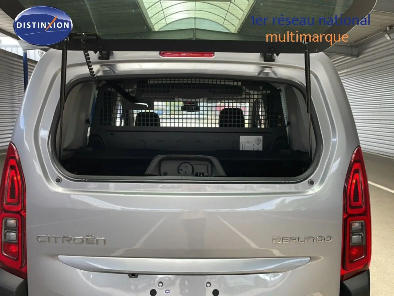 Vue arrière ouverte du Citroën Berlingo gris Artense métal, montrant l'intérieur utilitaire avec cloison de séparation.