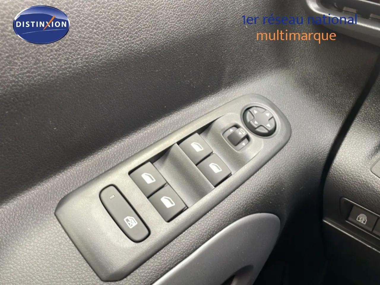Gros plan sur les commandes des vitres électriques et rétroviseurs côté gauche du Citroën Berlingo gris 2026.