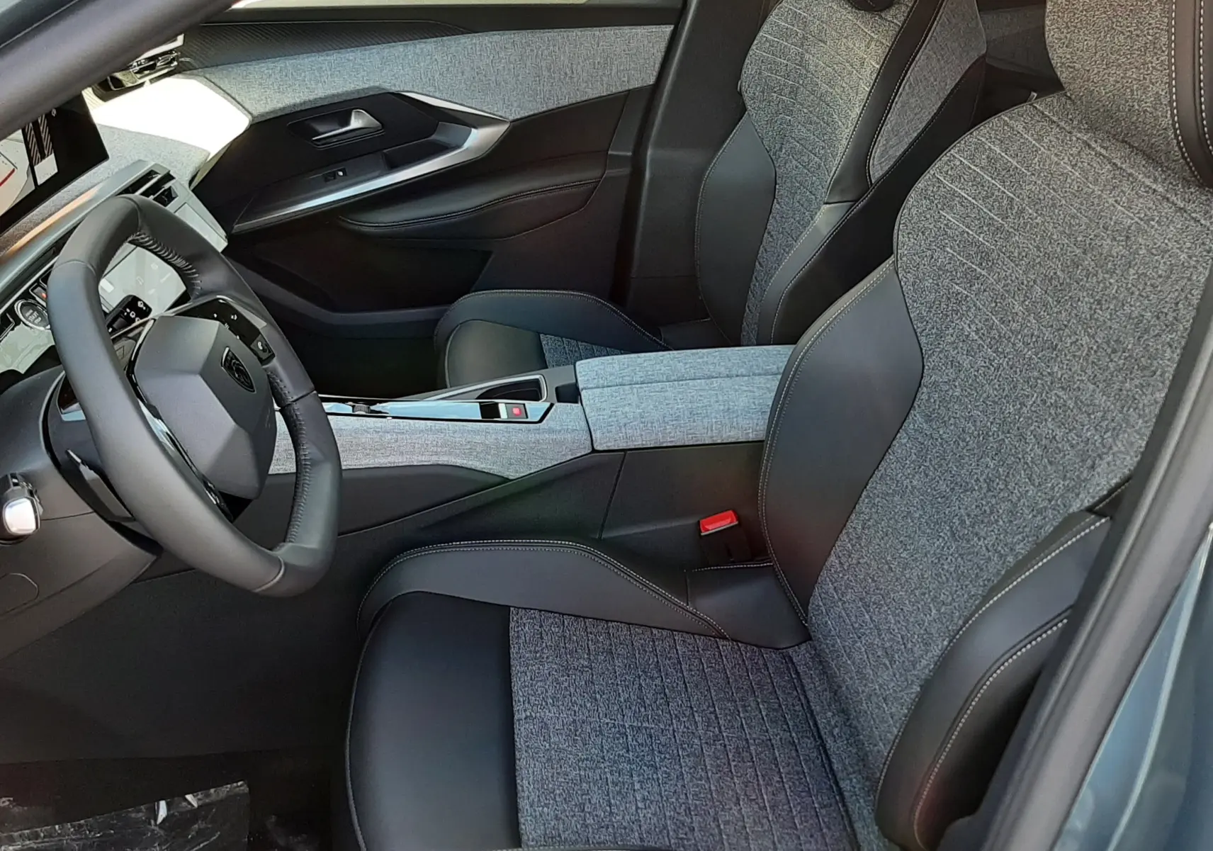Intérieur du Peugeot 5008 2025 vu côté conducteur, sièges bi-matière gris et noir avec console centrale assortie.