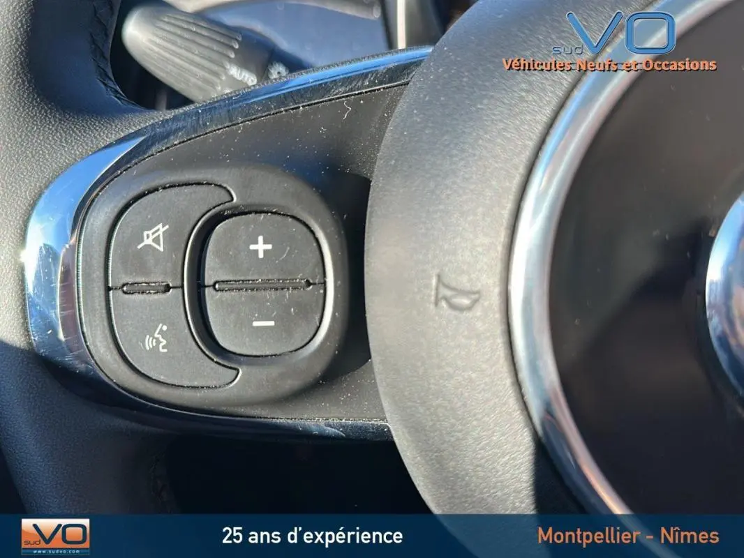 Gros plan sur les commandes vocales et volume au volant d'une FIAT 500C noire 2024, version hybride essence.