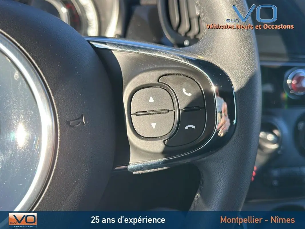 Gros plan sur les commandes du volant d'une FIAT 500C noire 2024, mettant en valeur les boutons de gestion d'appels téléphoniques.