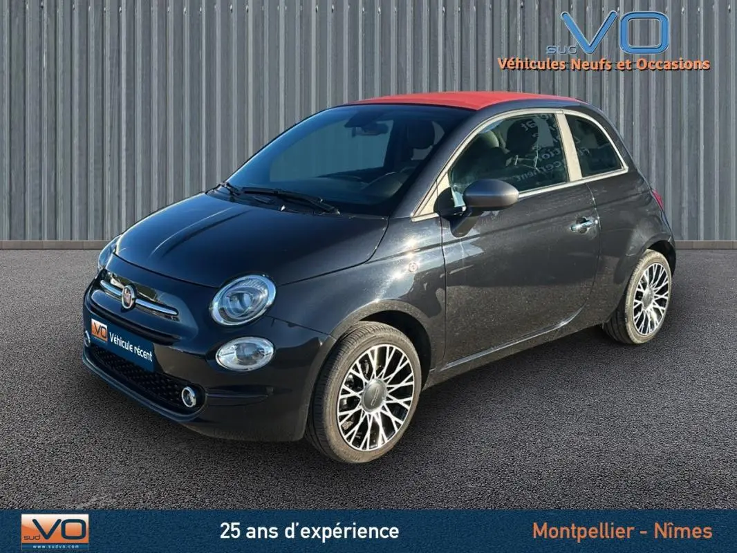 Vue 3/4 avant droite d'une FIAT 500C noire avec toit rouge et jantes alliage, modèle 2024 hybride essence.