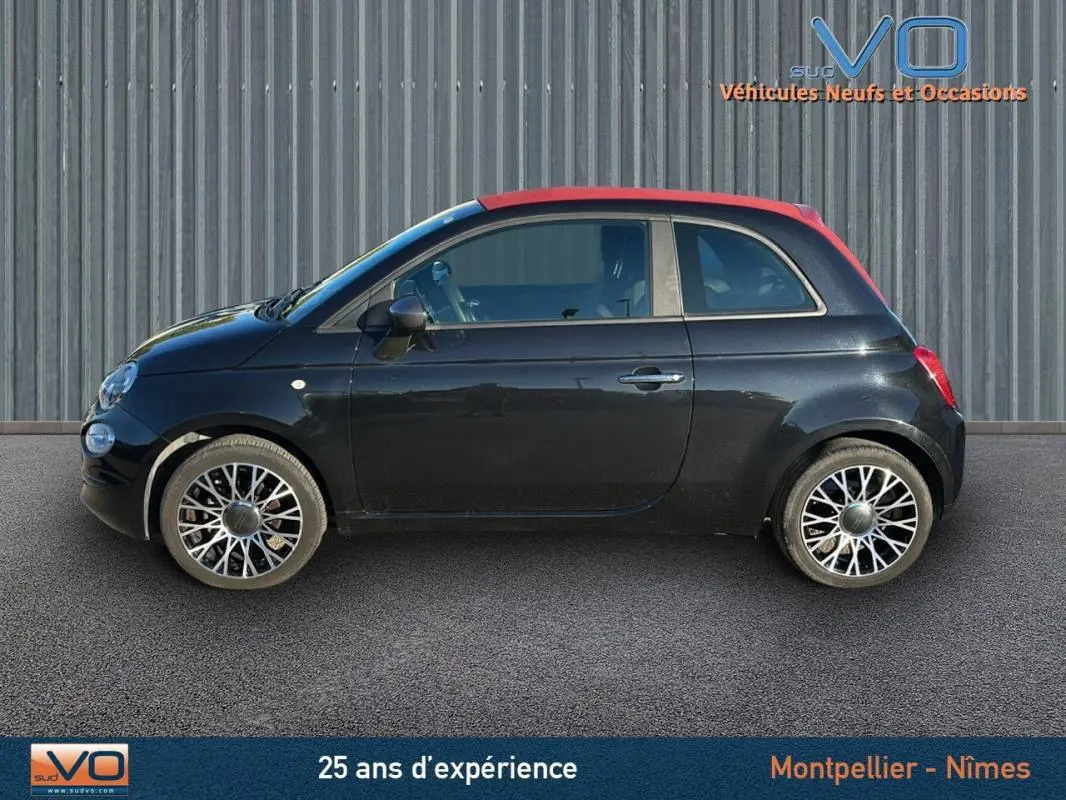 Profil côté gauche d'une FIAT 500C noire avec toit rouge, roues alliage et roue de secours visible, modèle 2024 hybride.