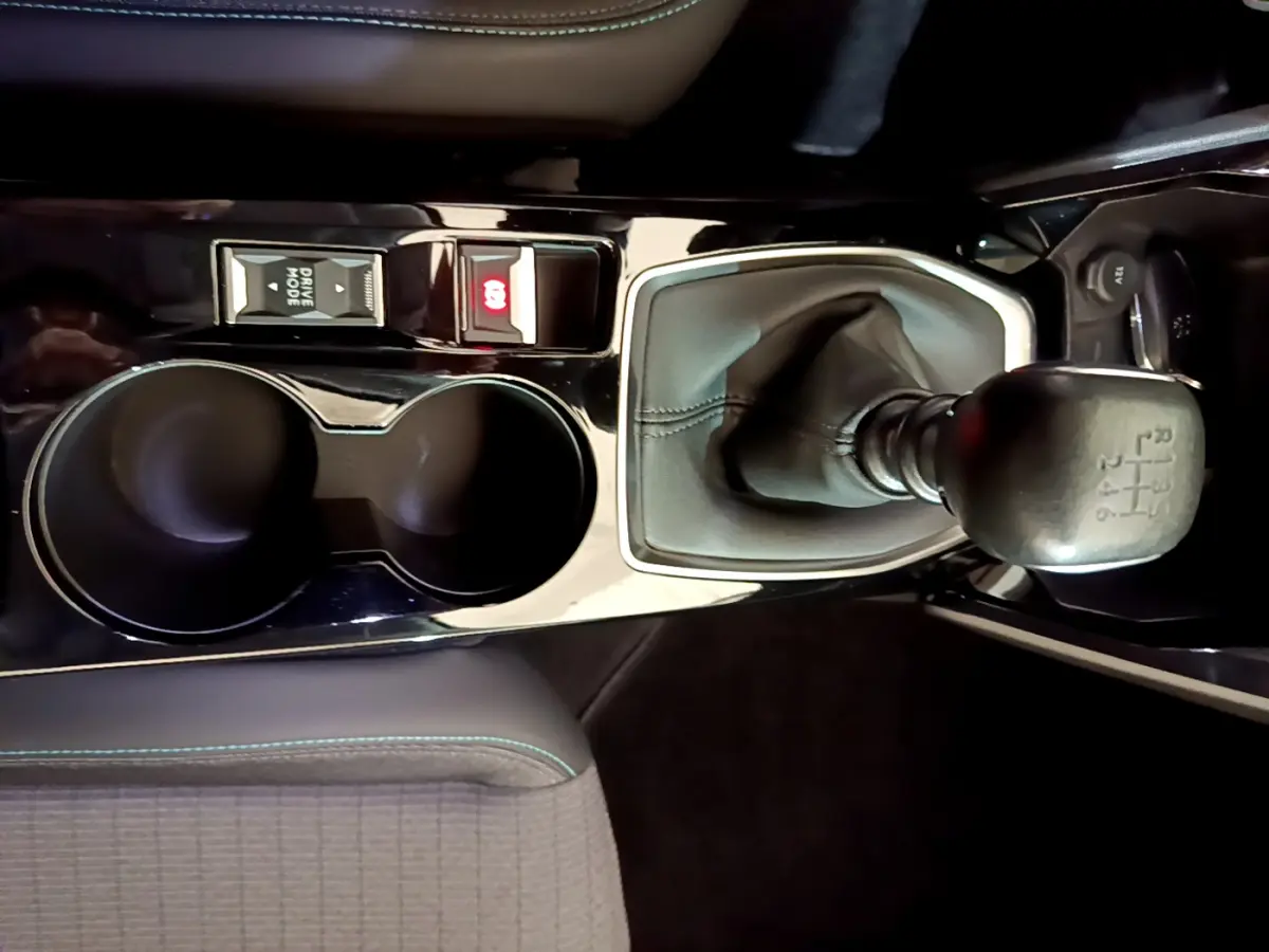 Vue rapprochée de la console centrale noire du Peugeot 2008 2021, avec levier de vitesses manuel et porte-gobelets.