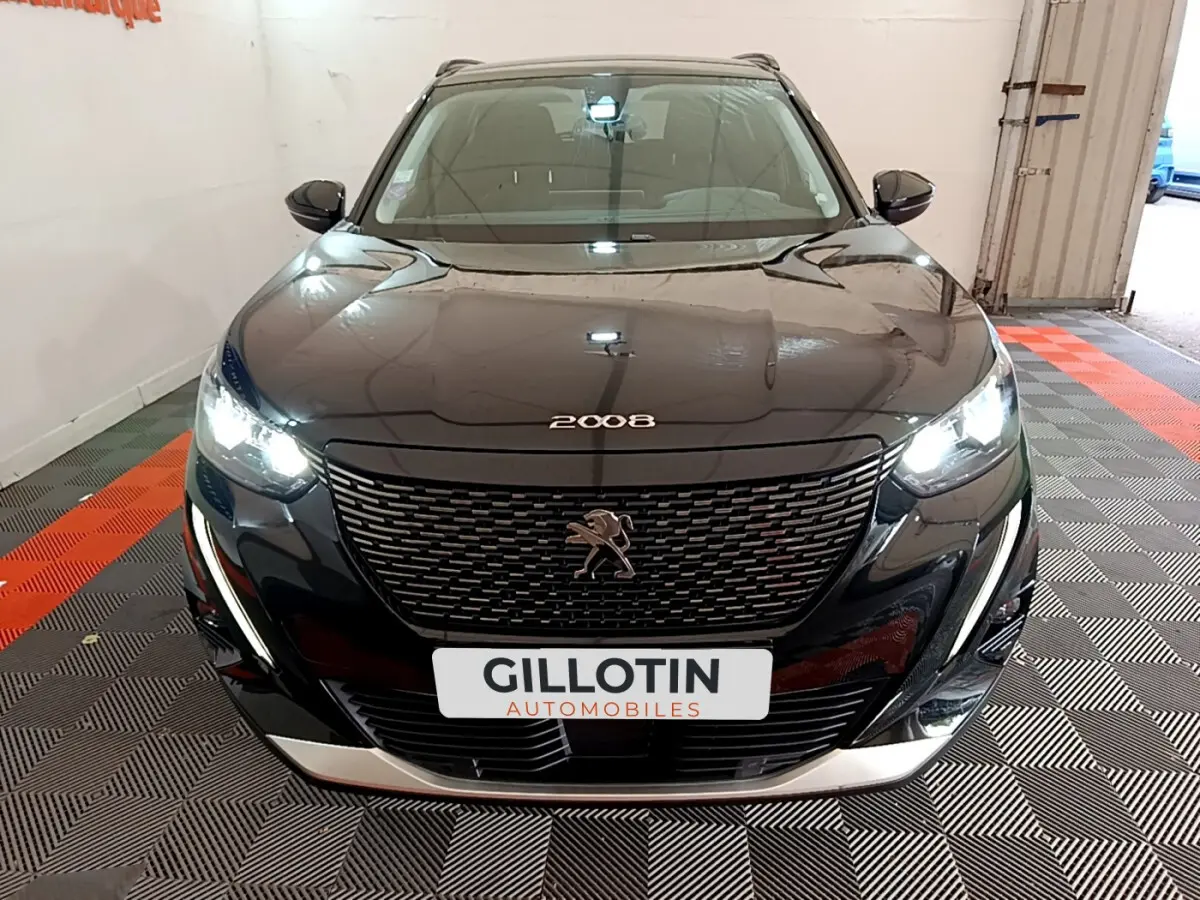 Peugeot 2008 noir vue de face avec phares LED allumés et calandre distinctive dans un garage.