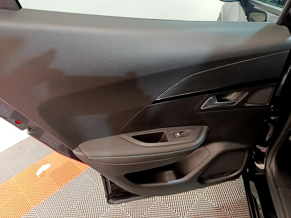 Vue rapprochée de la porte arrière droite noire du Peugeot 2008 avec garniture tissu et surpiqûres bleues.