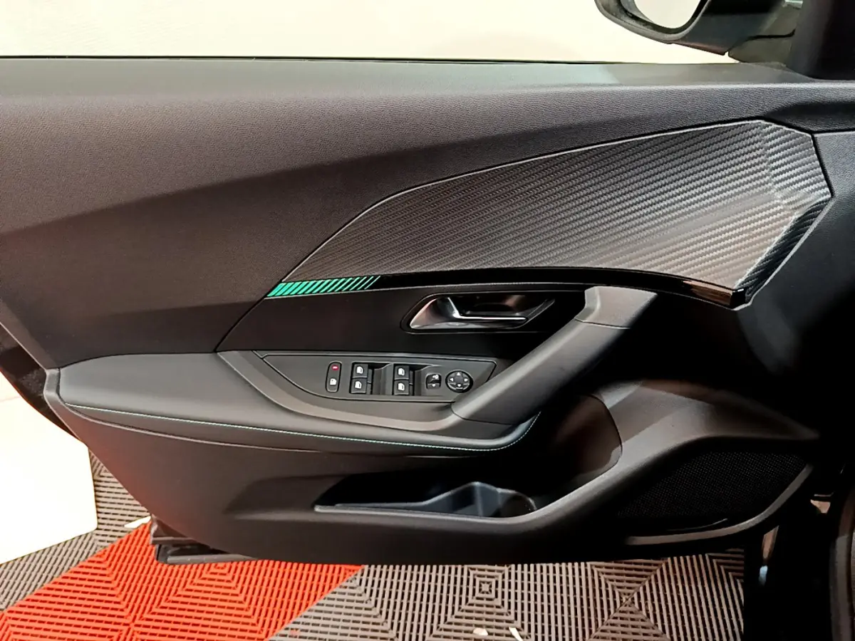 Vue rapprochée de la porte côté gauche noire du Peugeot 2008 avec insert effet carbone et commandes de vitres électriques.