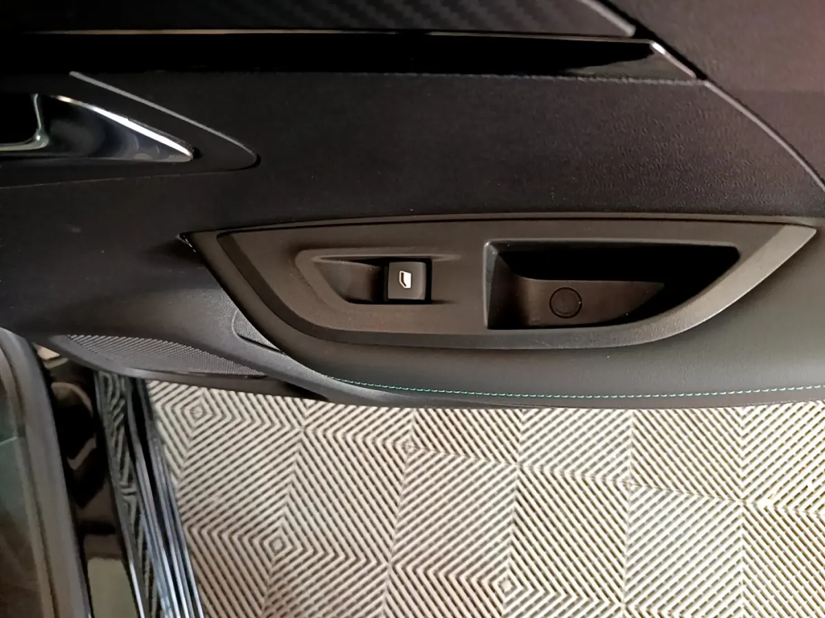 Poignée intérieure et commande de vitre côté gauche de la porte d'une Peugeot 2008 noire, finition Allure Business.