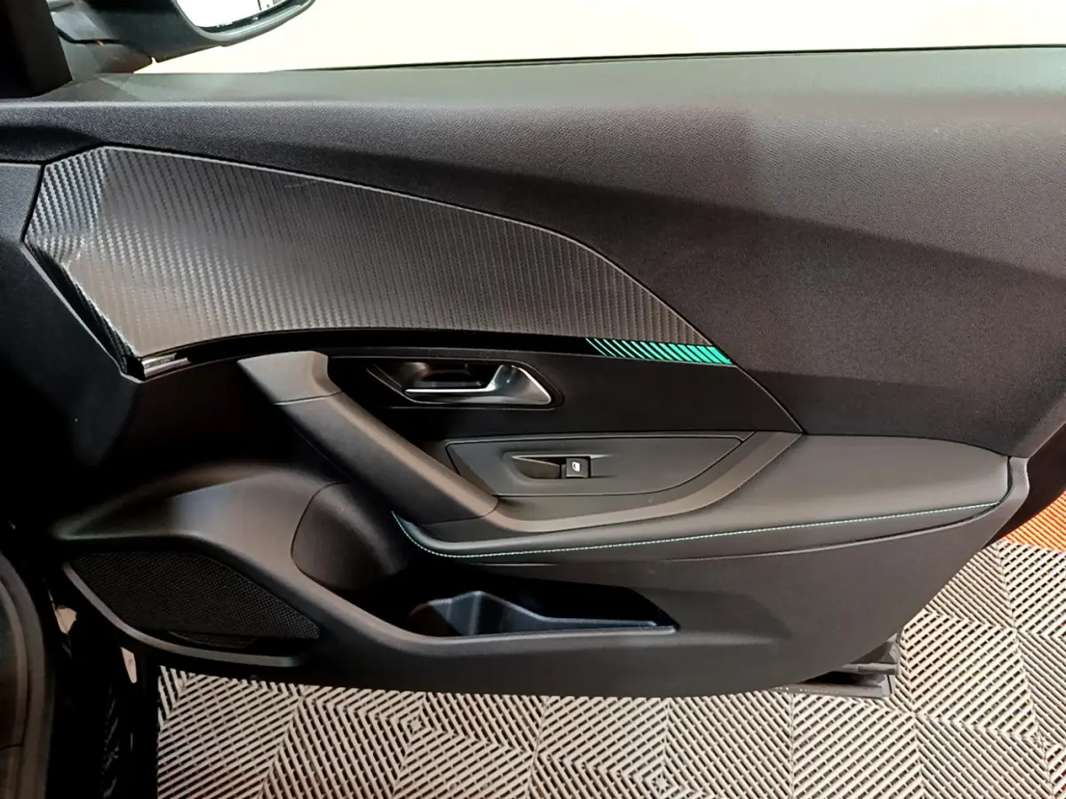 Vue côté gauche de la porte intérieure noire du Peugeot 2008 avec insert carbone et surpiqûres bleues.