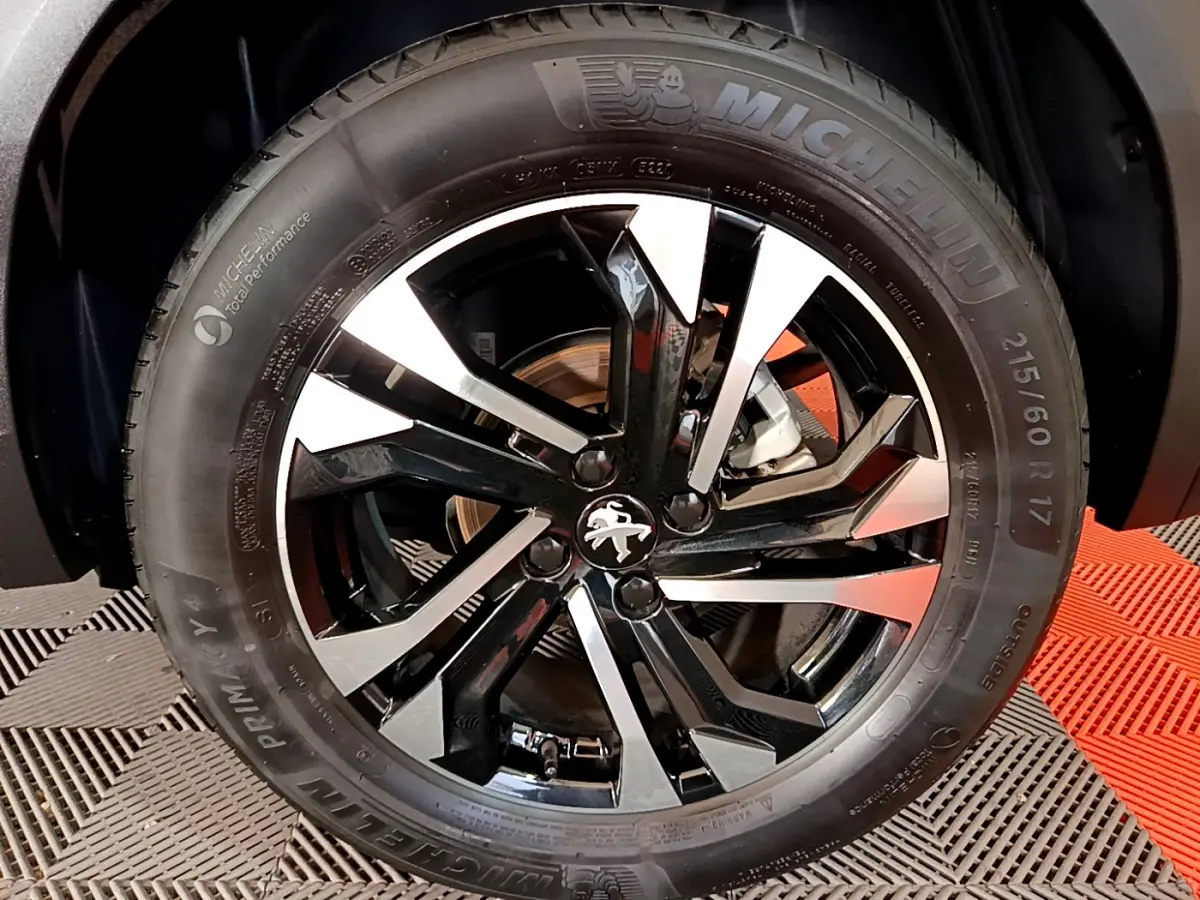 Gros plan sur la roue avant droite du Peugeot 2008 noir, jante alliage bicolore et pneu Michelin visible.