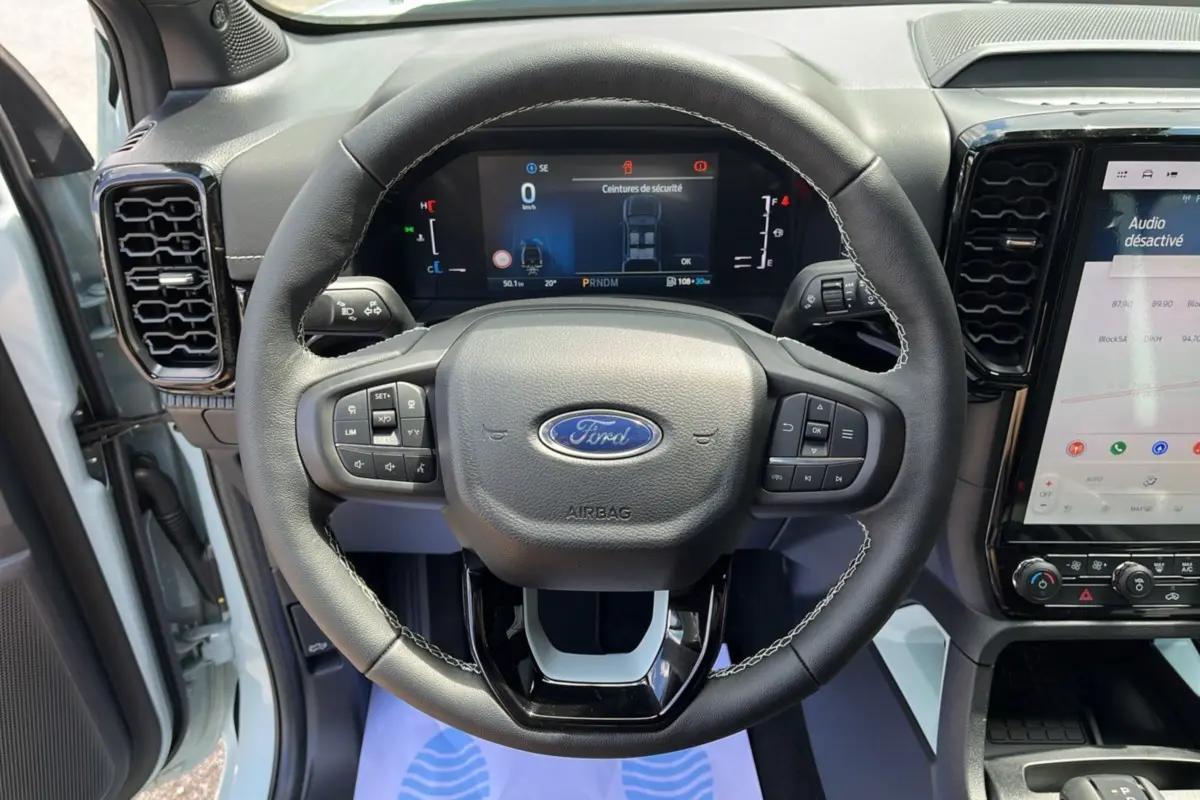 Vue intérieure centrée sur le volant cuir multifonctions du Ford Ranger gris zen avec tableau de bord digital et écran tactile.