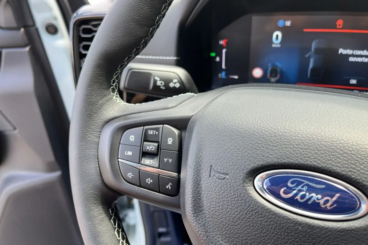 Gros plan sur le volant cuir multifonctions du Ford Ranger gris zen avec commandes intégrées et tableau de bord numérique.