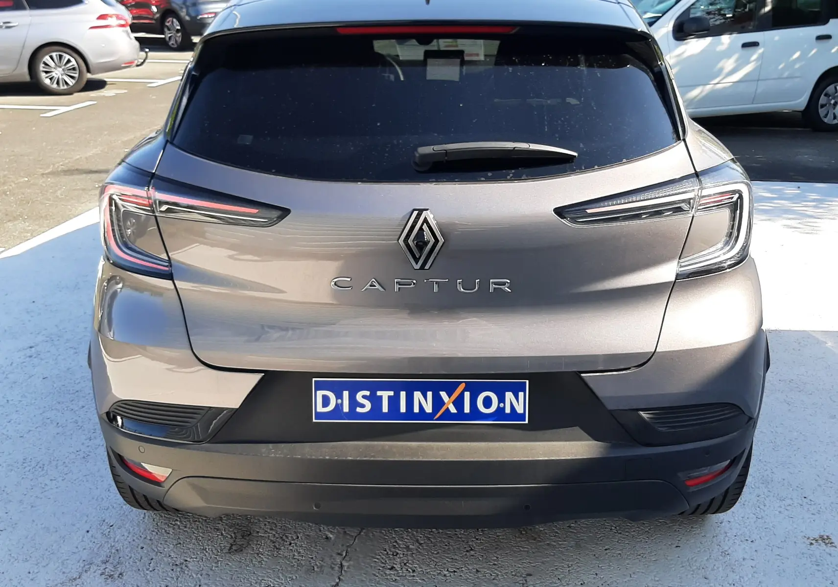 Vue arrière d'un Renault Captur gris Cassiopée 2025 avec feux LED et plaque Distinxion visible en extérieur.