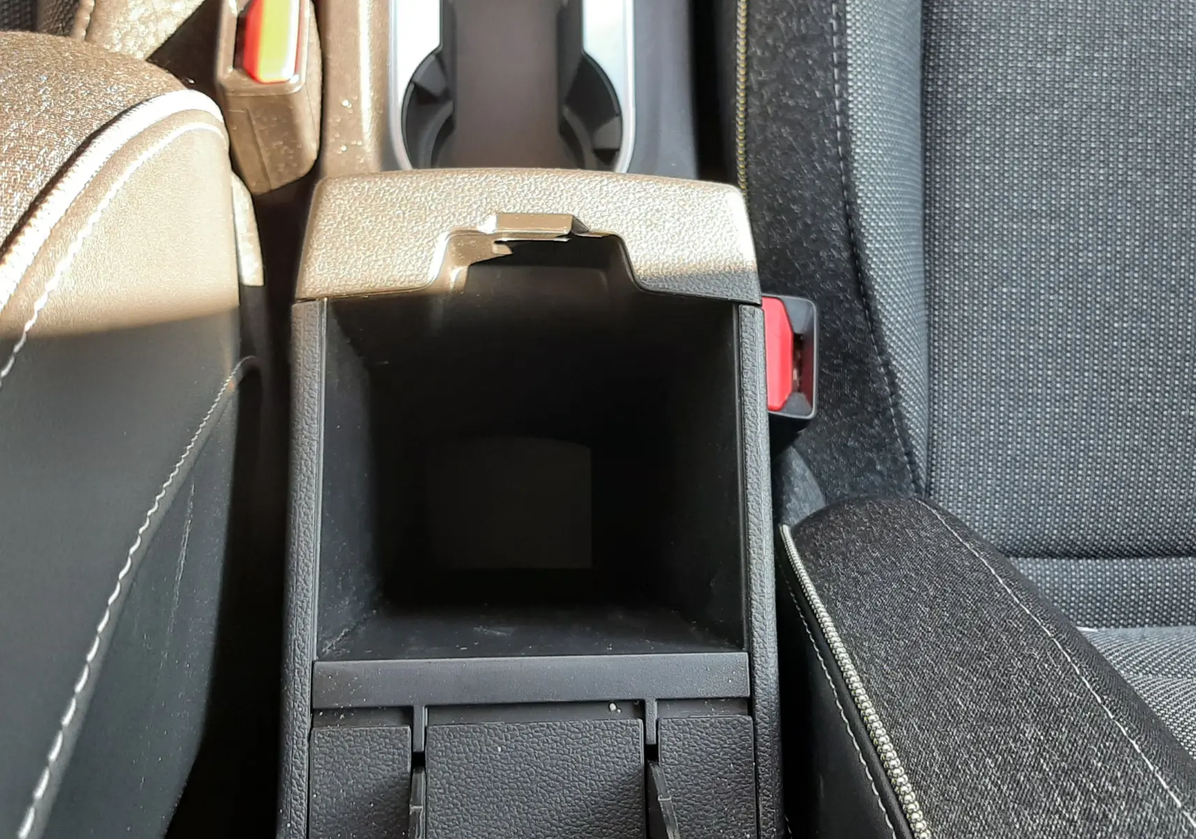 Vue plongeante sur le rangement central ouvert entre les sièges avant en tissu gris du Renault Captur II 2025.