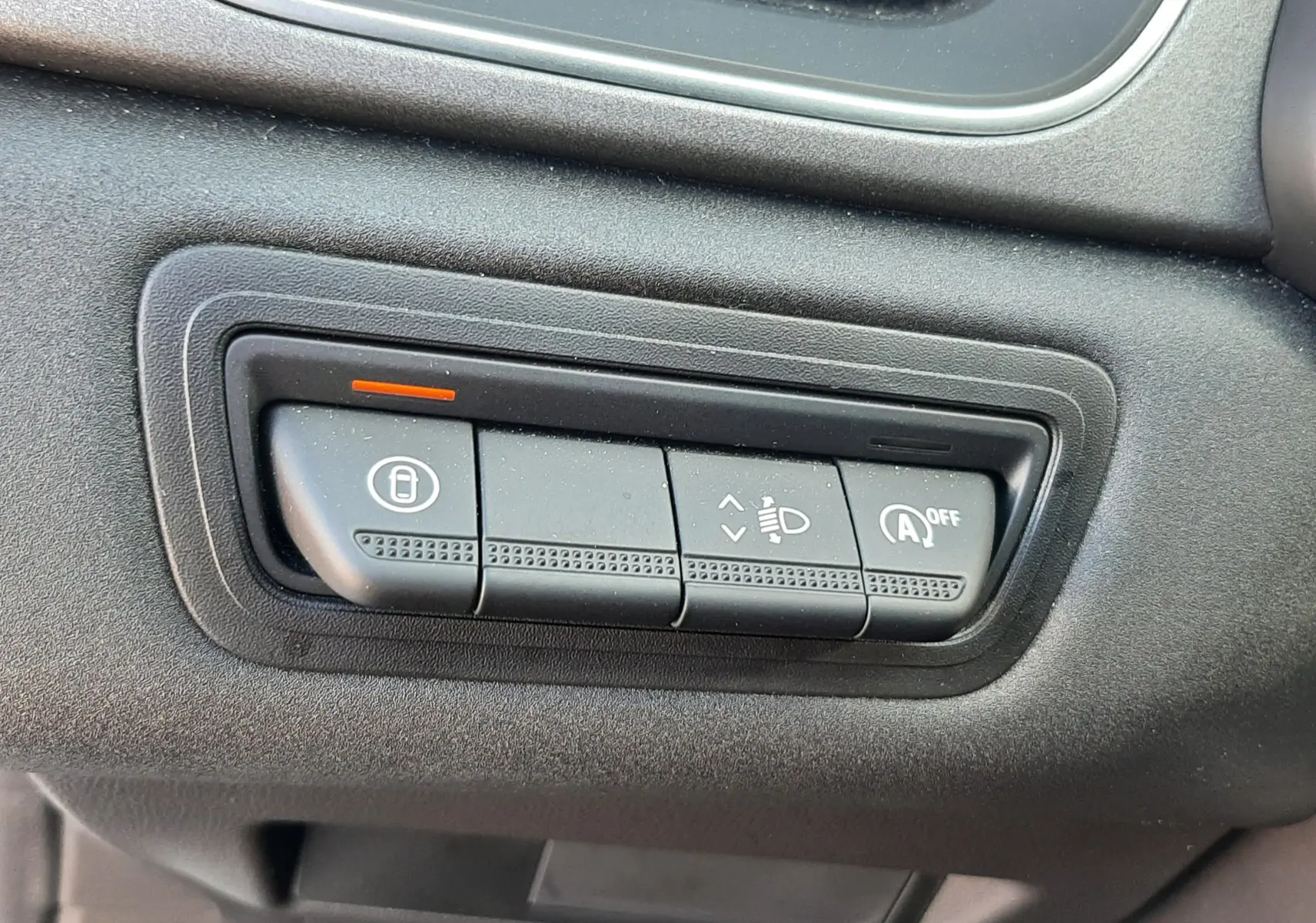 Gros plan sur les commandes de réglage des phares et du système start-stop, tableau de bord noir du Renault Captur gris Cassiopée.