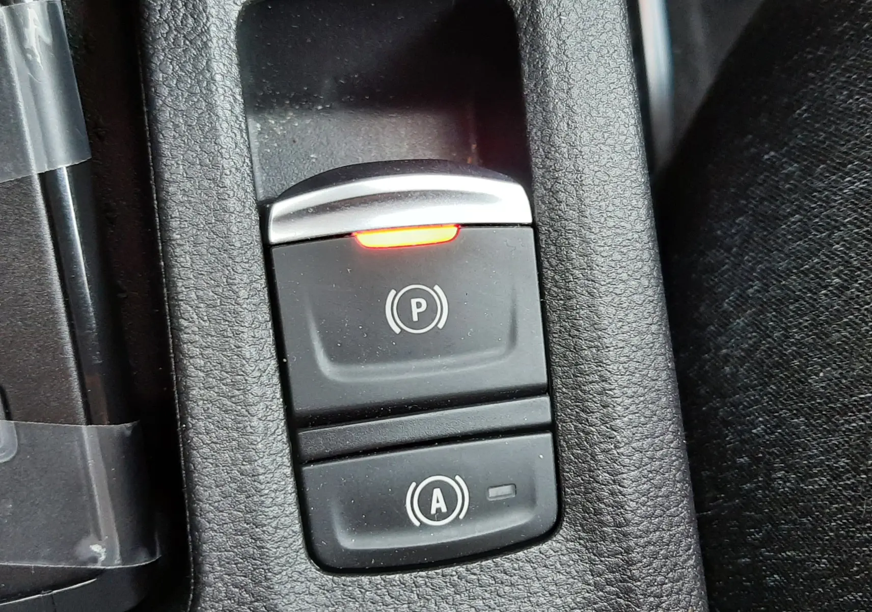 Gros plan sur les boutons de frein à main électronique et arrêt auto du Renault Captur gris Cassiopée, intérieur tissu noir.