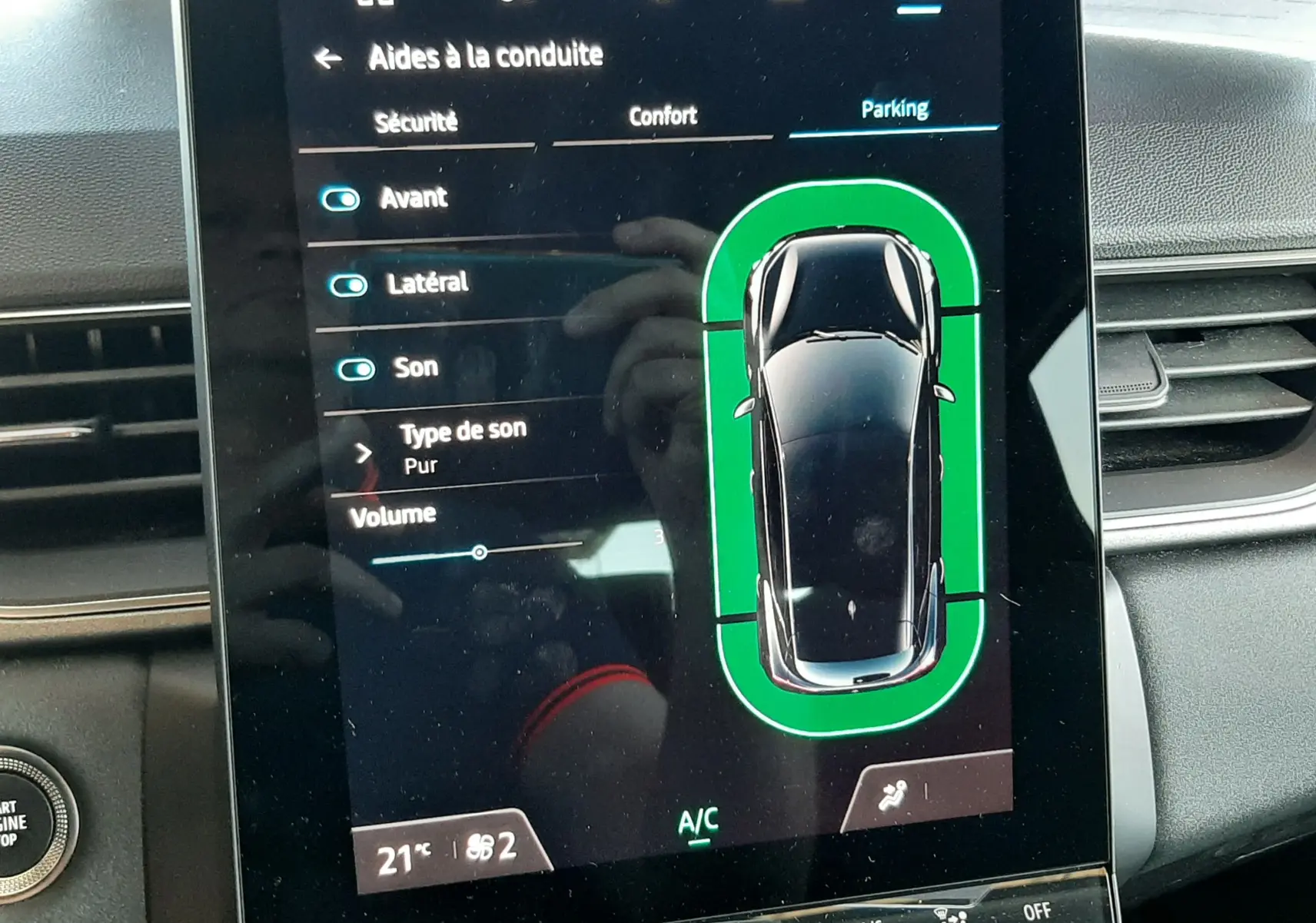 Écran tactile intérieur du Renault Captur II gris Cassiopée montrant l'aide au stationnement avec vue du dessus du véhicule.