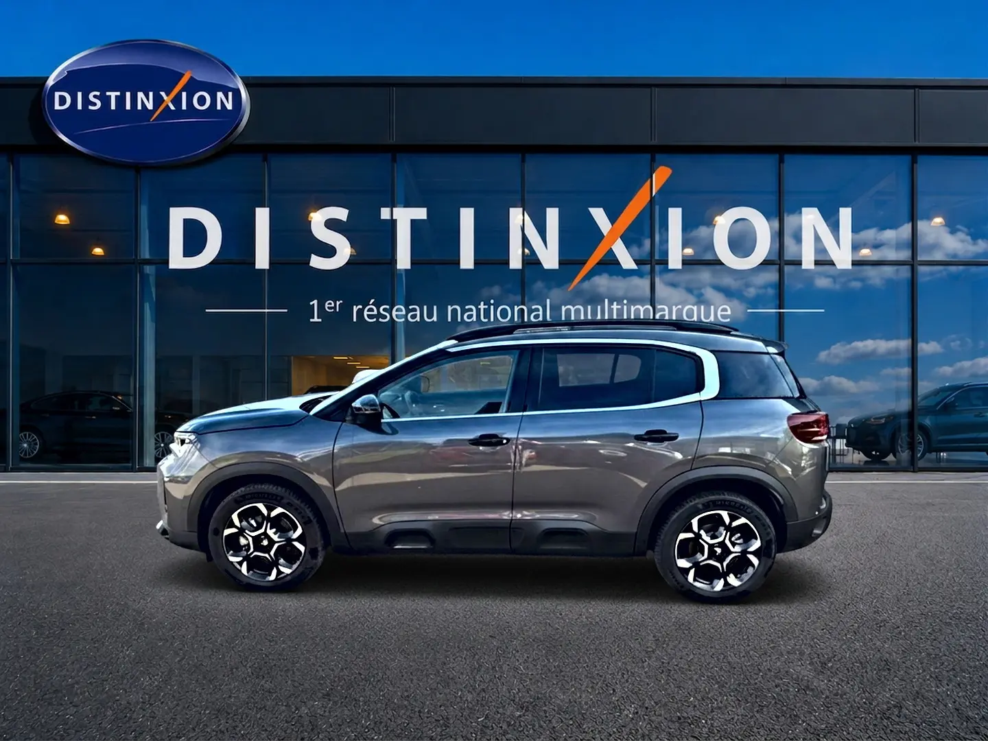 Profil côté gauche d'un Citroën C5 Aircross gris 2025 avec jantes alu et barres de toit visibles.