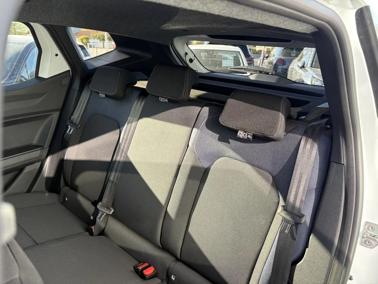 Vue intérieure arrière droite du Dacia Duster 2024 blanc, montrant la banquette arrière en sellerie Denim avec appuie-têtes et ceintures de sécurité.