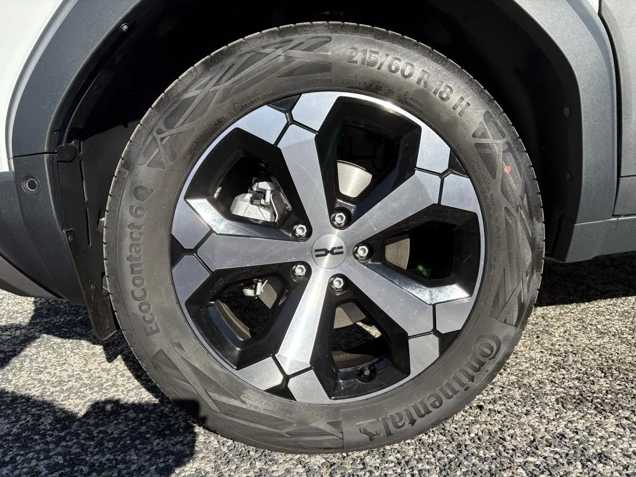 Gros plan sur la jante alliage 18 pouces noire et argent du Dacia Duster 1.6 Hybrid blanc métallisé, côté droit.