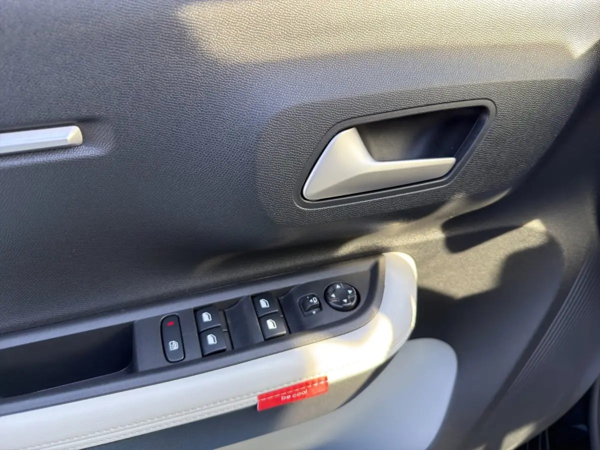 Gros plan sur la porte intérieure côté conducteur de la Citroën C3 noire, avec commandes des vitres et poignée argentée.