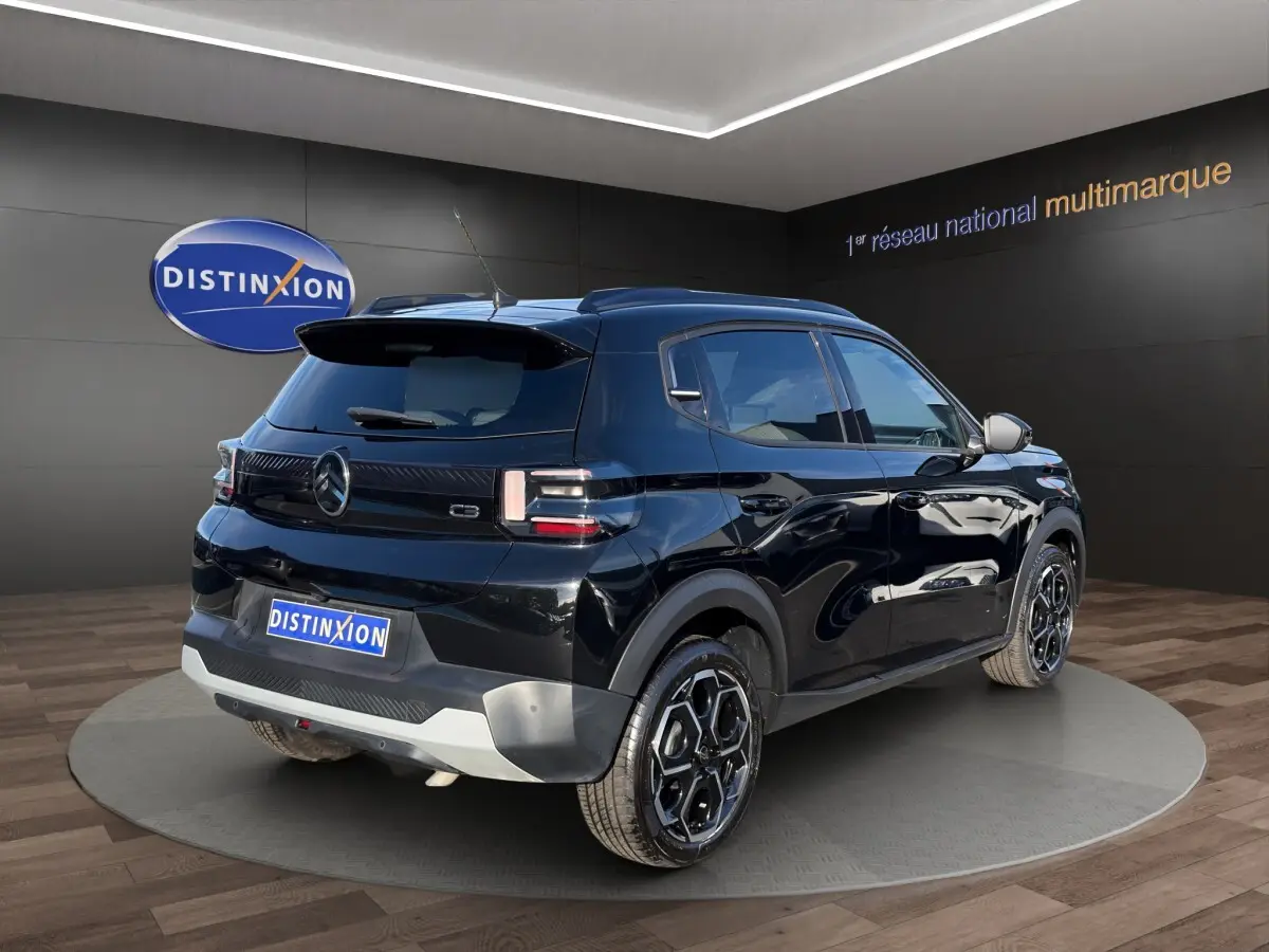 Vue 3/4 arrière droite d'une Citroën C3 Turbo 100 BVM6 MAX noire avec jantes noires et toit noir en showroom.