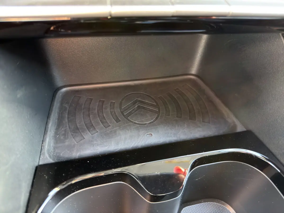 Gros plan sur la zone de recharge par induction avec logo Citroën embossé, intérieur noir brillant de la C3 Turbo 2025.