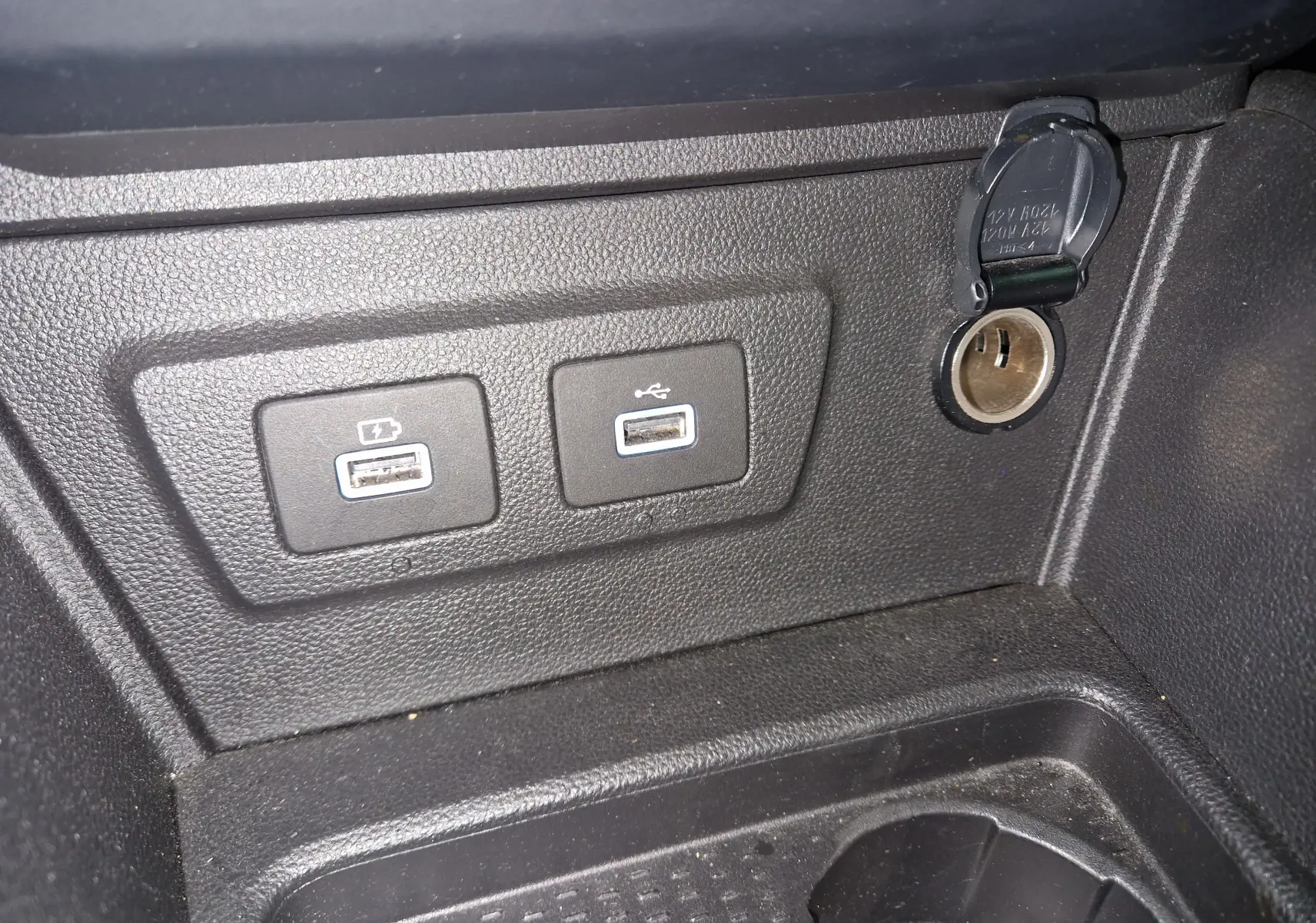 Prise 12V et deux ports USB intégrés dans la console centrale noire du Dacia Duster 2024, version 4x4 blanche.