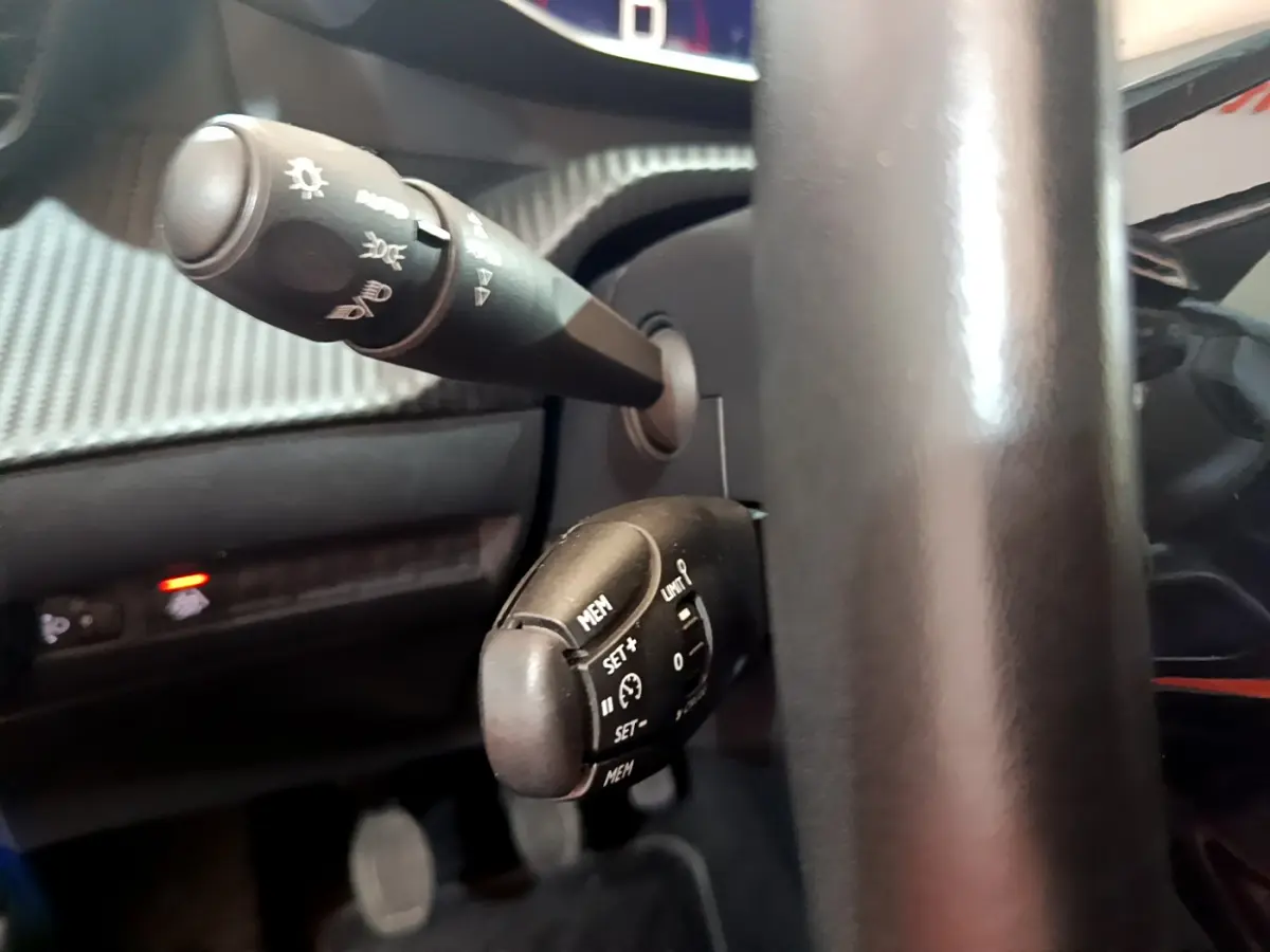 Gros plan sur les commandes au volant noir du Peugeot 2008 gris clair, mettant en valeur les boutons de régulateur de vitesse.