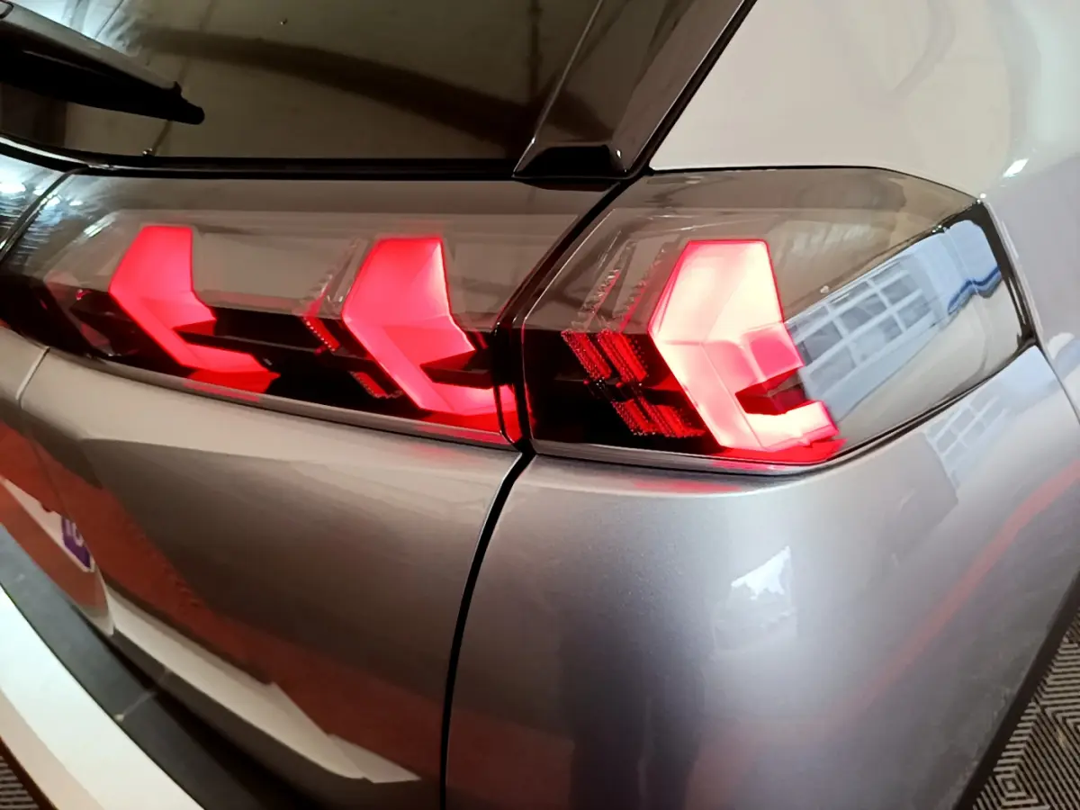 Gros plan sur les feux arrière rouges du côté gauche d’un Peugeot 2008 gris clair 2021, finition Allure Business.