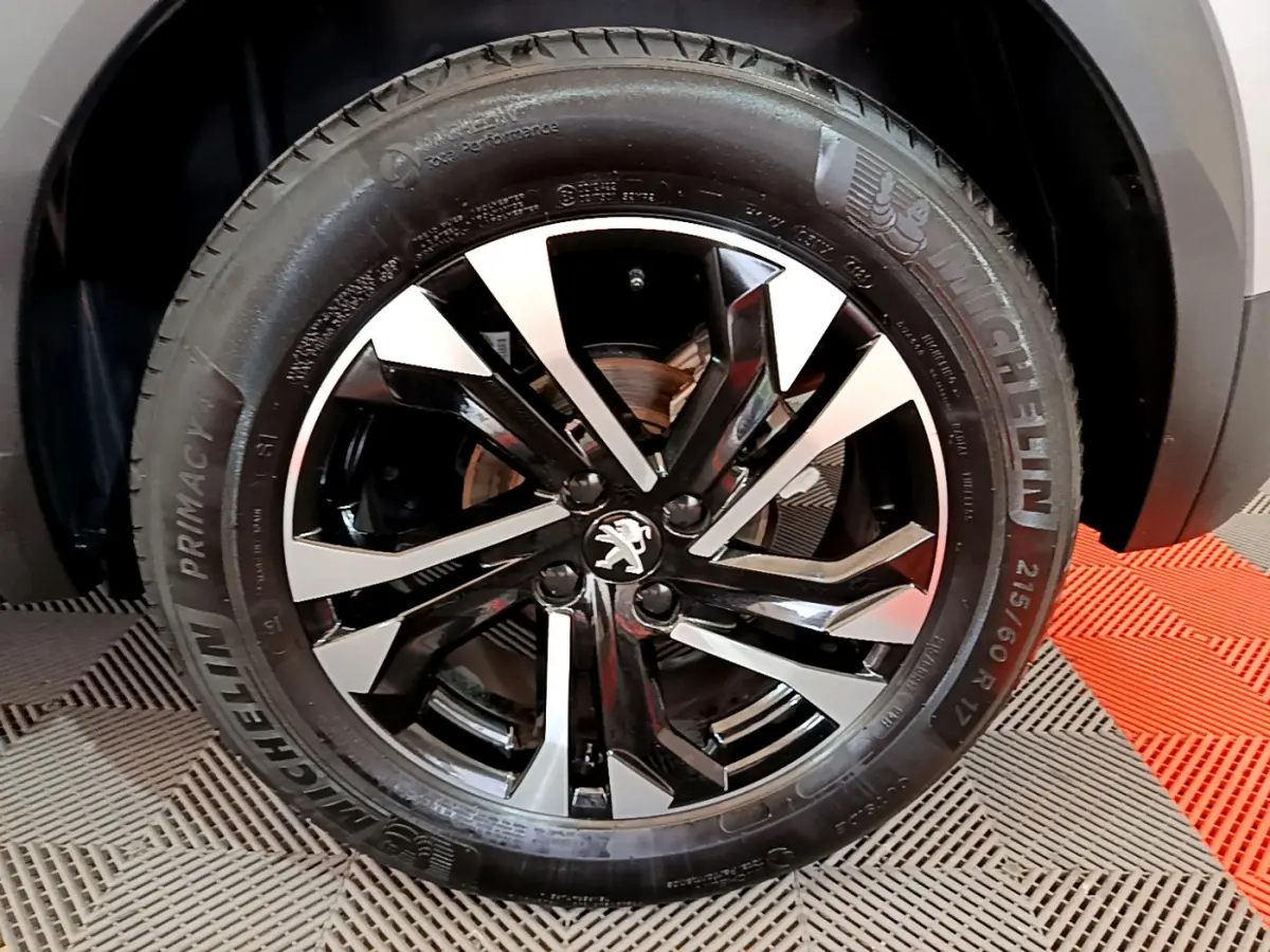 Gros plan sur la jante noire et argentée du côté droit du Peugeot 2008 gris clair, avec pneu Michelin visible.