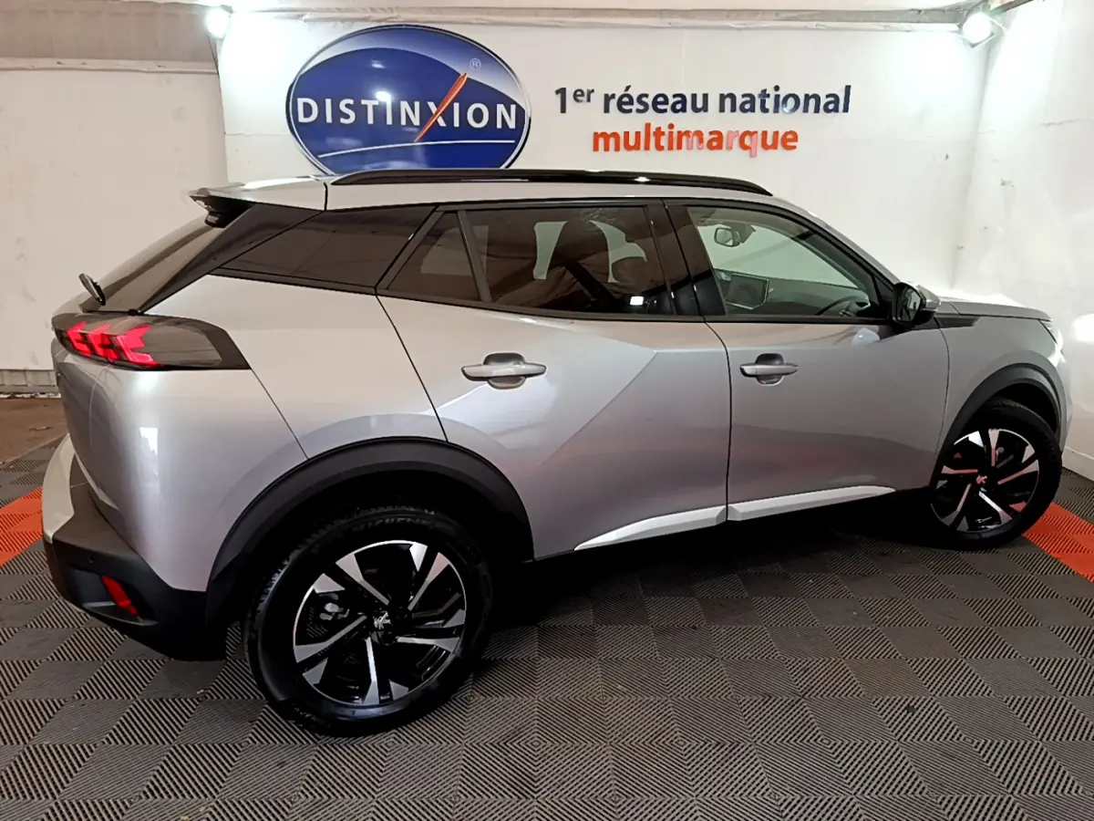 Peugeot 2008 gris clair vue de profil côté gauche, avec toit noir et jantes alliage noires distinctives.