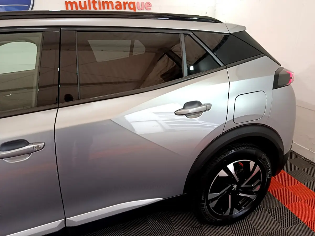 Vue latérale côté droit d'un Peugeot 2008 gris clair avec jantes noires et toit noir contrasté.