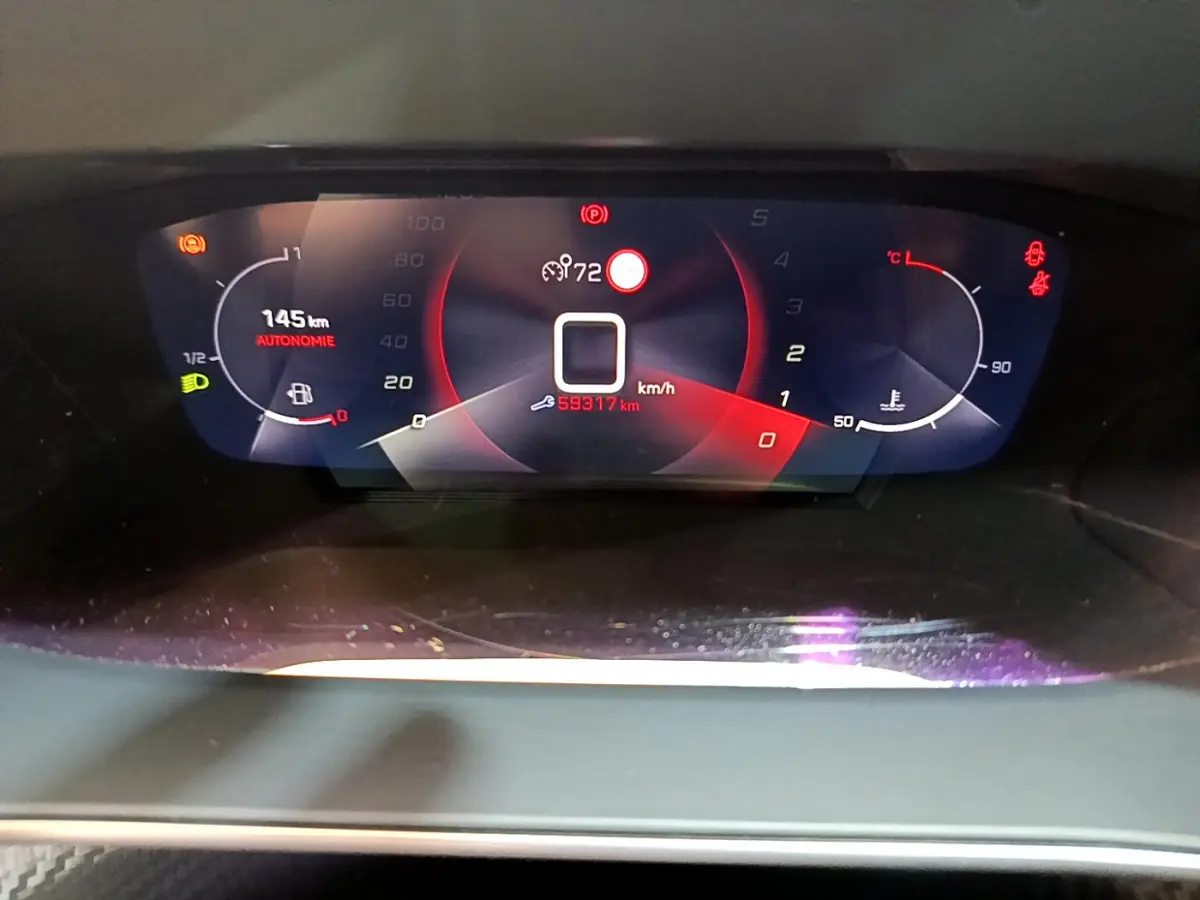 Vue rapprochée du tableau de bord numérique du Peugeot 2008 gris clair, affichant autonomie, vitesse et température moteur.